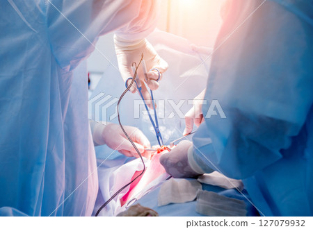 Surgeon and assistants in operating room with surgery equipment. 127079932
