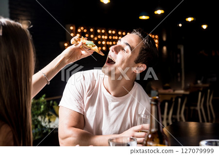 Cheerful friends in the pub. Drinking beer, eating pizza, talking, having fun. 127079999