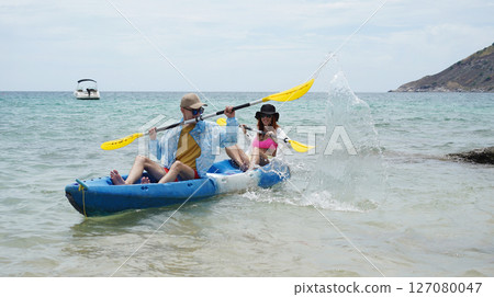 The young couple are happily navigating together in a light blue kayak with yellow paddles 127080047