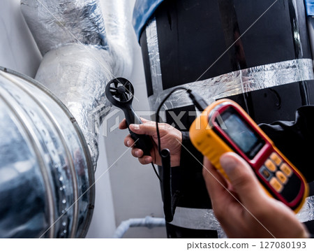 Technician use hand-held anemometer measuring air flowing measurement 127080193