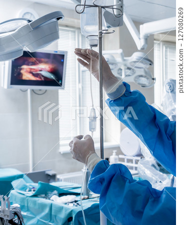 Medical drip tubing and patient at the hospital. 127080269