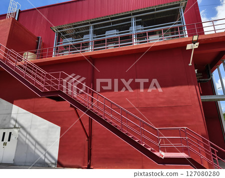 A set of stairs ascending a large red wall 127080280