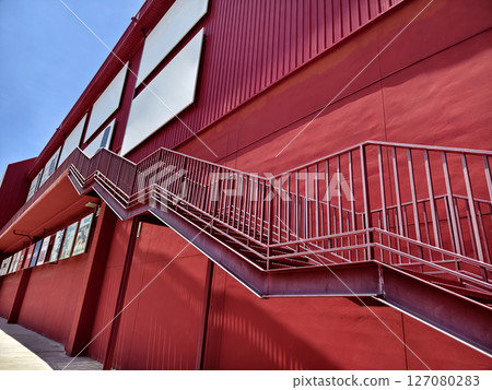 A set of stairs ascending a large red wall A set of stairs ascending a large red wall 127080283