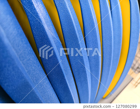 This image features a closeup view of a blue and yellow striped plastic. 127080299