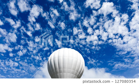 White hot air balloon against vibrant blue cloudy sky White hot air balloon against vibrant blue cloudy sky 127080354