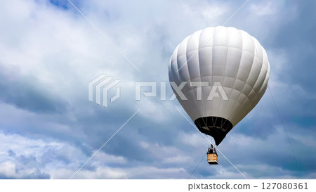 White hot air balloon against cloudy sky in scenic outdoor adventure scene White hot air balloon against cloudy sky in scenic outdoor adventure scene 127080361