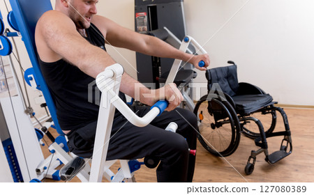 Disabled man doing strength exercises separate from the wheelchair. 127080389