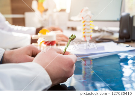 Doctor show polyaxial screw on the spine model. Spine fixation systems Doctor show polyaxial screw on the spine model. Spine fixation systems 127080410