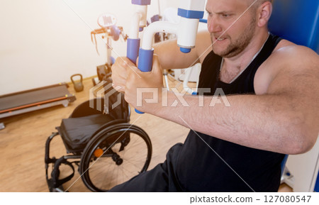 Disabled man doing strength exercises separate from the wheelchair. Disabled man doing strength exercises separate from the wheelchair. 127080547