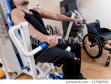 Disabled man doing strength exercises separate from the wheelchair. 127080585