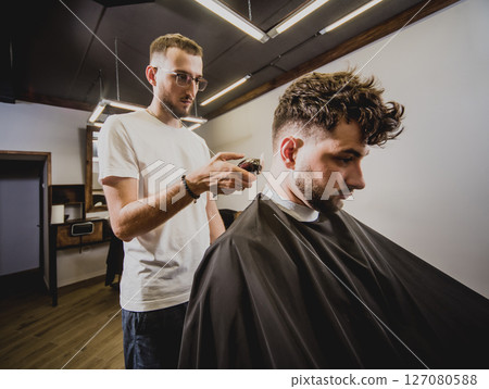 Young man with trendy haircut at barber shop.  127080588