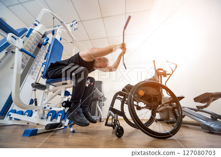 Disabled man doing strength exercises separate from the wheelchair. 127080703