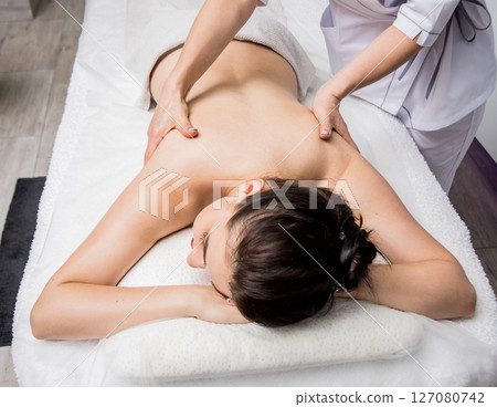 Beautiful young woman enjoying massage in spa salon. Cosmetology 127080742