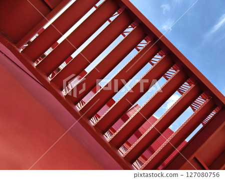 A set of stairs ascending a large red wall 127080756