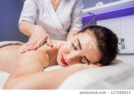 Beautiful young woman enjoying massage in spa salon. Cosmetology 127080813