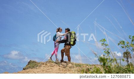 A young couple are hiking on a rugged rocky cliff that offers a view of the ocean 127080871