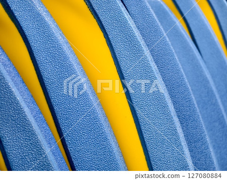This image features a closeup view of a blue and yellow striped plastic. This image features a closeup view of a blue and yellow striped plastic. 127080884
