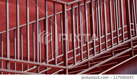 A set of stairs ascending a large red wall 127080885
