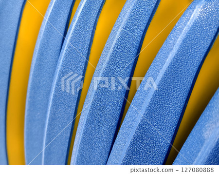 This image features a closeup view of a blue and yellow striped plastic. 127080888