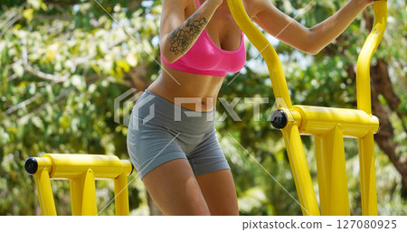 A young woman are exercising on a machine in a park A young woman are exercising on a machine in a park 127080925