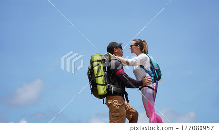 A young couple are hiking on a rugged rocky cliff that offers a view of the ocean 127080957