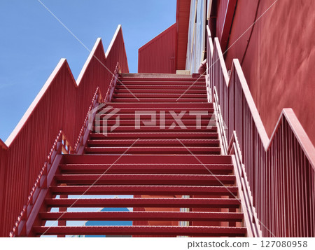 A set of stairs ascending a large red wall 127080958