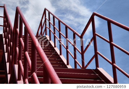 A set of stairs ascending a large red wall 127080959