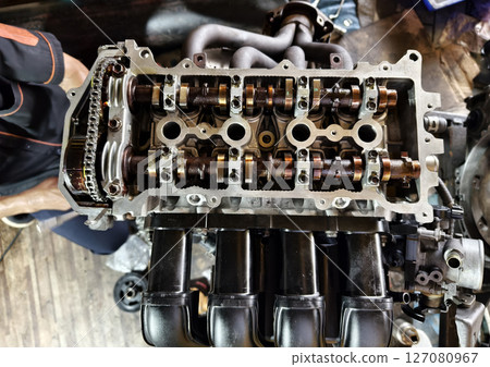 A car engine is being worked on inside a garage workshop A car engine is being worked on inside a garage workshop 127080967