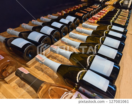 A variety of bottles of champagne are elegantly lined up on a wooden shelf 127081061