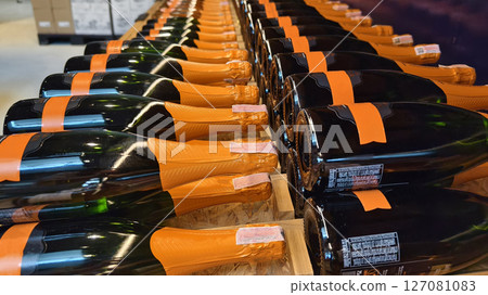 A variety of bottles of champagne are elegantly lined up on a wooden shelf 127081083