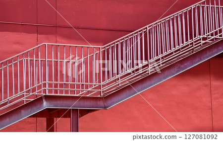 A set of stairs ascending a large red wall 127081092