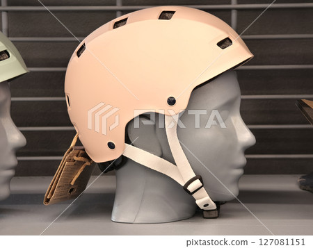 A variety of different colored helmets are neatly hanging on a rack A variety of different colored helmets are neatly hanging on a rack 127081151