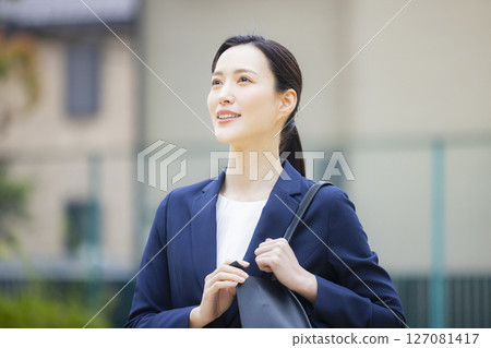 一位身著西裝的年輕女子走過居民區 127081417