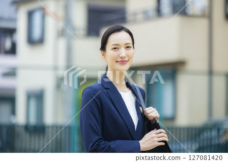 A young woman in a suit walking through a residential area 127081420