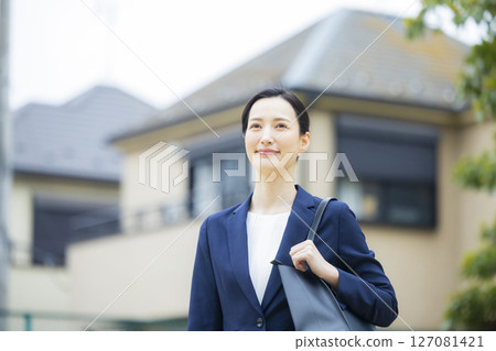 一位身著西裝的年輕女子走過居民區 127081421
