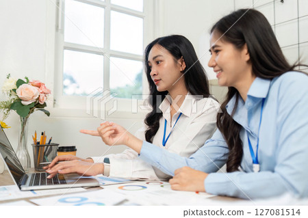Teamwork and Engagement. Women collaborating on a laptop in a bright office setting. 127081514