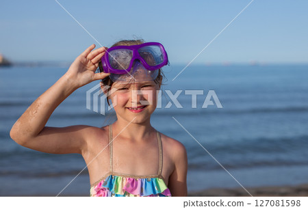Toddler girl with purple snorkeling goggles at the beach on a sunny day 127081598