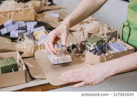 Person stamps kraft packaging near handmade soaps, dried lavender, and eco-friendly filler. Visual identity for makers, slow brand values, minimalist packaging, artisanal design Person stamps kraft packaging near handmade soaps, dried lavender, and eco-friendly filler. Visual identity for makers, slow brand values, minimalist packaging, artisanal design 127081684