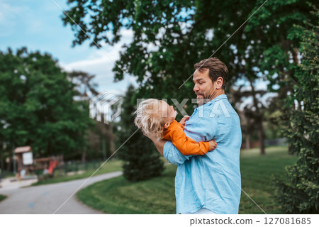 Father playing with toddler son outdoors in park 127081685
