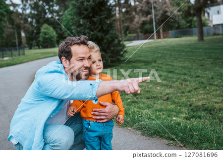 Dad showing his toddler son something in the distance. Dad showing his toddler son something in the distance. 127081696