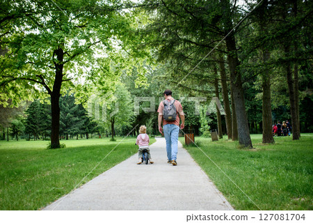 Rear view of father walking with his son across park Rear view of father walking with his son across park 127081704
