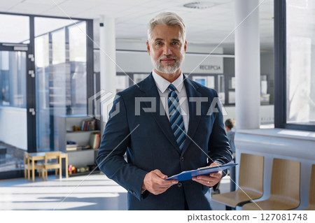 Confident senior manager holding documents in modern clinic.t 127081748