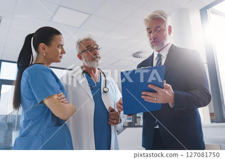 Medical sales representative presenting new medication to doctors, standing hospital hallway. 127081750