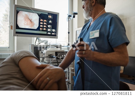 Doctor looking at monitior during gastroscopy procedure, examining upper digestive tract. 127081811