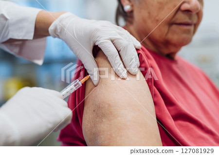 Elderly patient being vaccinated by doctor. Elderly patient being vaccinated by doctor. 127081929