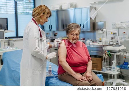 Elderly patient being vaccinated by doctor. Elderly patient being vaccinated by doctor. 127081938