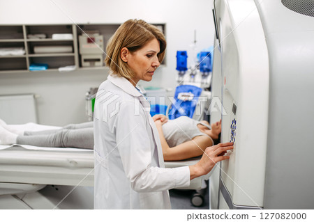 Doctor operating CT machine and preparing patient for scan 127082000