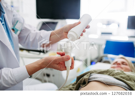 Radiologist applying gel to ultrasound probe before abdominal scan 127082038