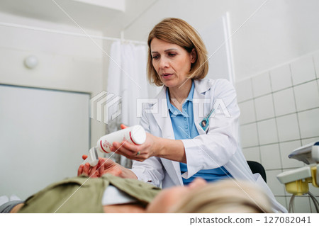 Radiologist applying gel to ultrasound probe before abdominal scan 127082041