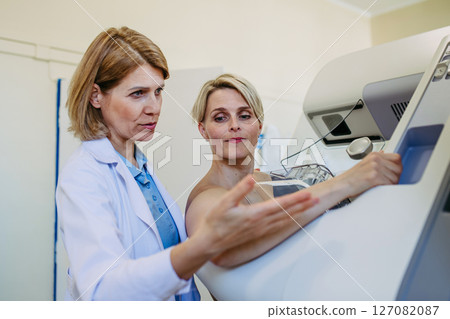 Healthcare professional adjusts the patient for accurate breast imaging. 127082087